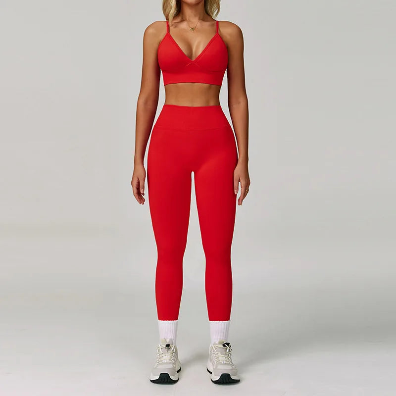 Eine Frau trägt ein rotes, nahtloses Sport-Yoga-Set mit Crop-Top und Langhosen.