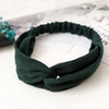 Dark green bohemian chiffon headband tied in a knot resting on a white surface.