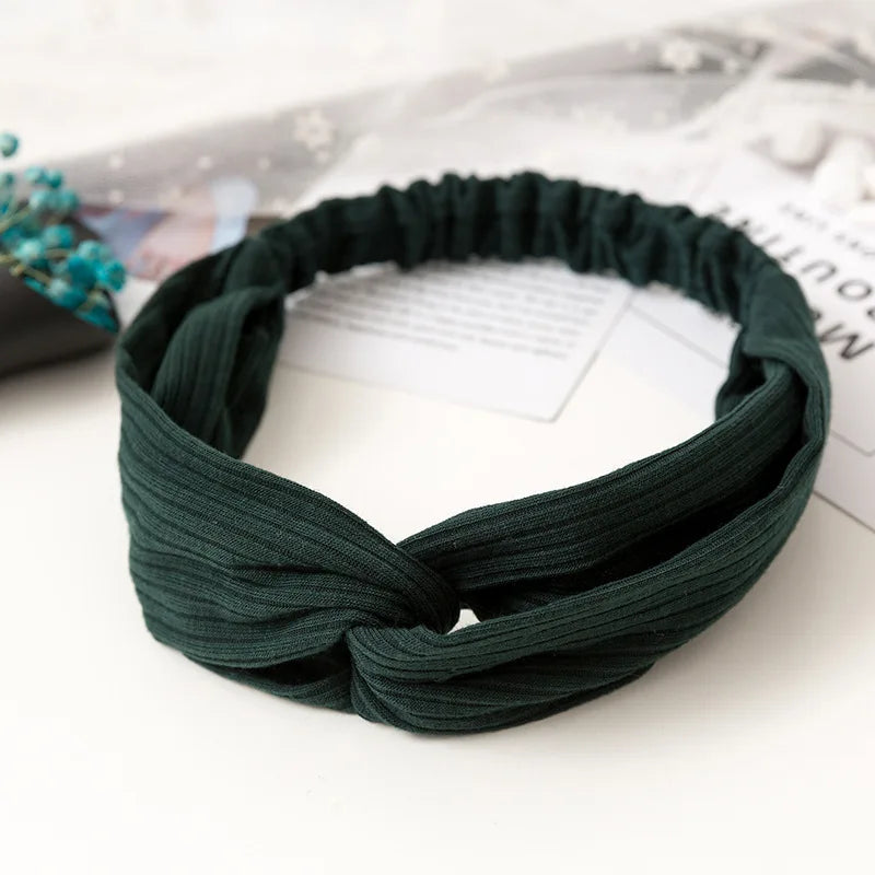 Dark green bohemian chiffon headband tied in a knot resting on a white surface.