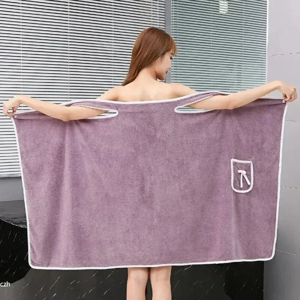 A woman wearing a purple soft fleece bath robe stands in front of a slatted window.