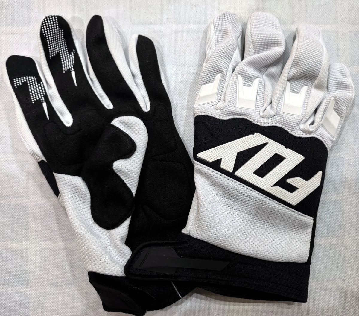 A pair of black and white durable motorcycle off-road riding gloves displayed on a white background.