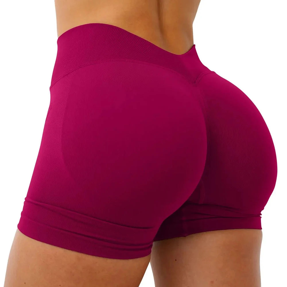 A close-up view of a woman wearing seamless magenta yoga shorts.