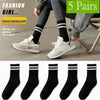 A model wearing gray pants and white sneakers with black striped socks, showcasing a classic trendy outfit.