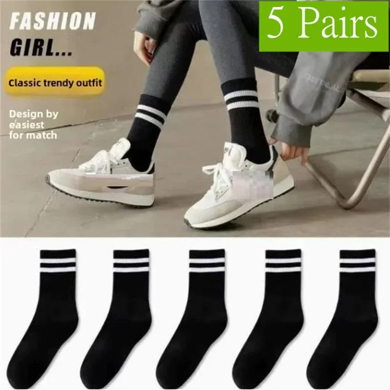 A model wearing gray pants and white sneakers with black striped socks, showcasing a classic trendy outfit.