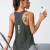 A woman wearing a dark gray running and yoga vest with a stylized letter design, sitting on a chair.