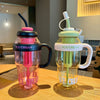 A clear reusable water bottle filled with pink ice cream, featuring a silicone straw and handle.