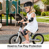 A young girl wearing a black helmet and protective gear is riding a silver bicycle outdoors.
