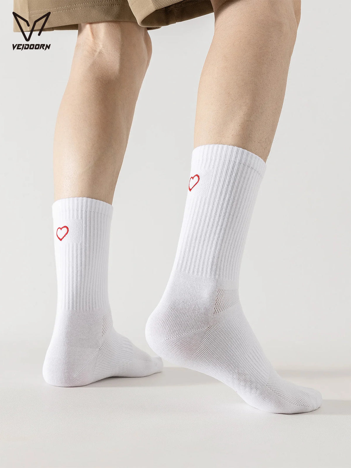 A pair of white crew socks with red heart embroidery worn on a person's legs.