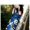Una botella de agua azul para ciclismo sostenida por una mano, colocada en un cuadro de bicicleta blanca en un entorno exteri