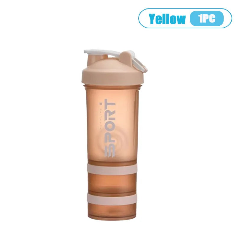 A clear, three-layer protein shaker bottle with a beige cap and handle.