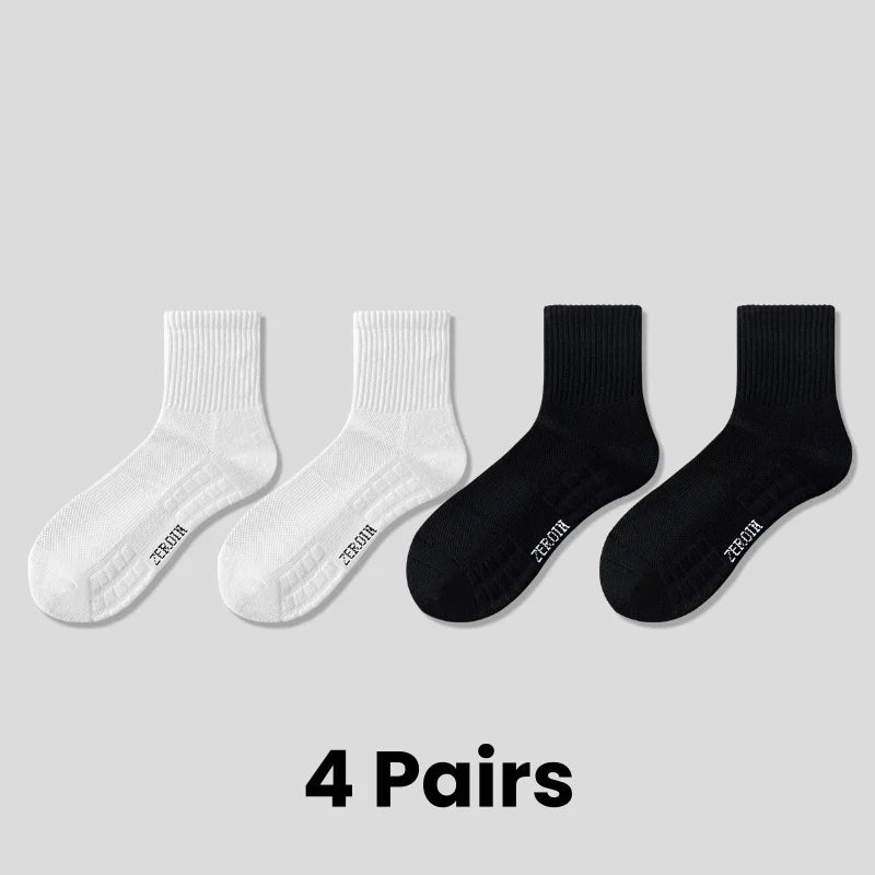 Four pairs of white and black breathable sports performance socks laid out on a light gray background.