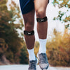Close-up of a person's legs wearing black knee braces and white socks while running outdoors.