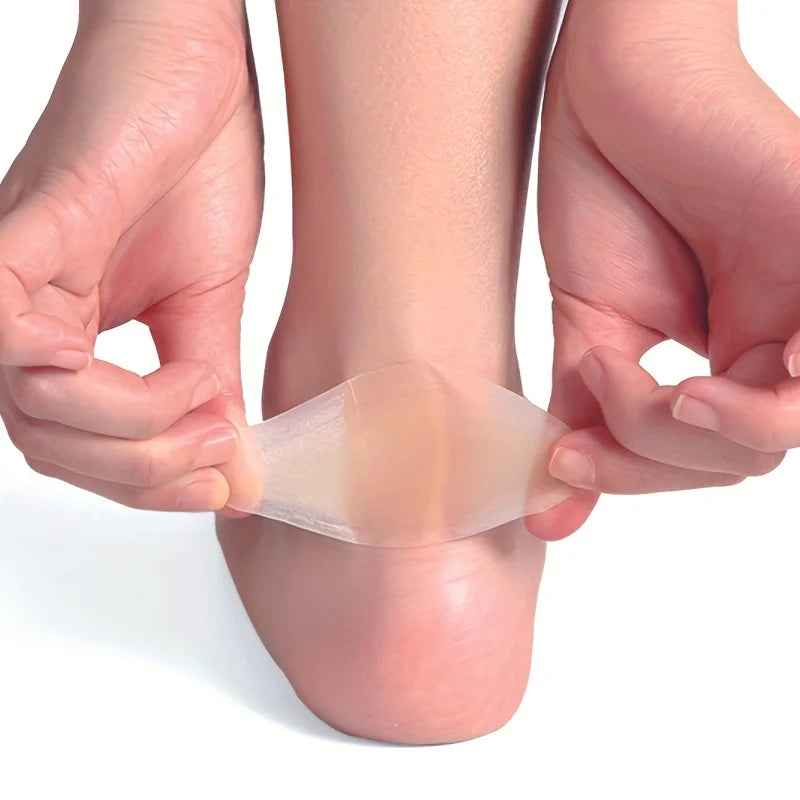 Hands are applying a clear silicone blister patch to the sole of a foot for protection.