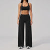 A woman wearing a black two-piece yoga and sports tracksuit set consisting of a cropped top and loose pants.