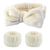 A set of white microfiber spa headband and wristband, shown folded and rolled.