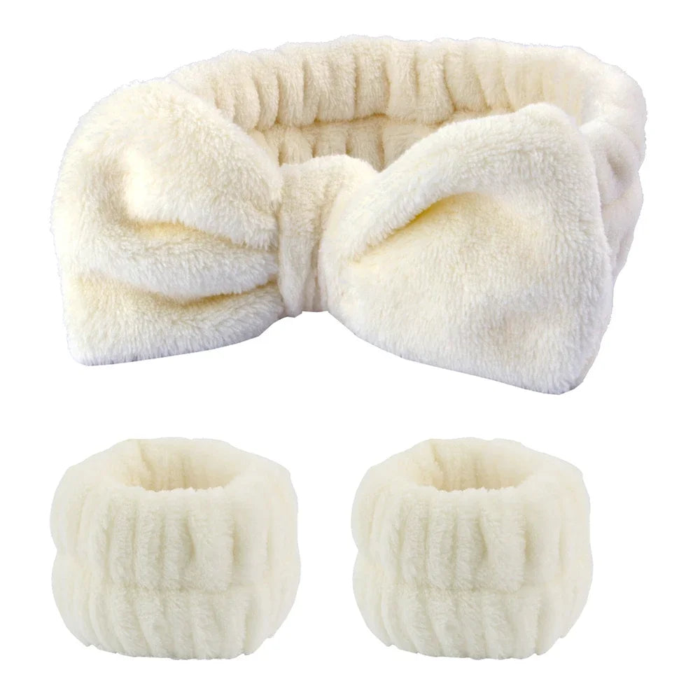 A set of white microfiber spa headband and wristband, shown folded and rolled.