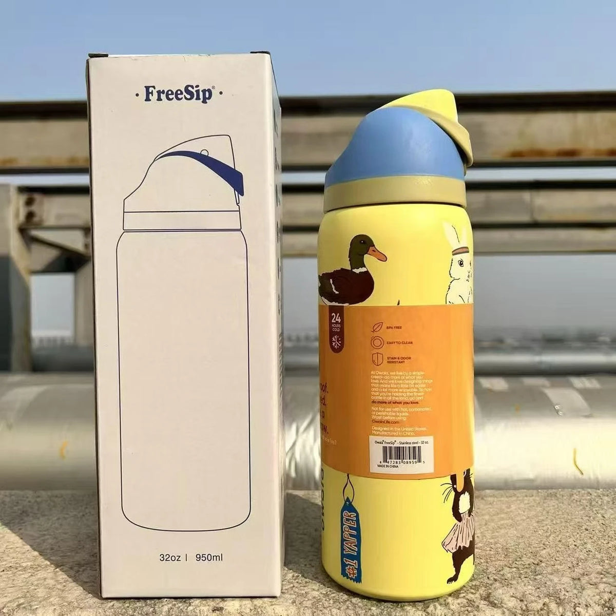 A yellow vacuum insulated water bottle with a straw and a duck graphic is shown next to its packaging box.
