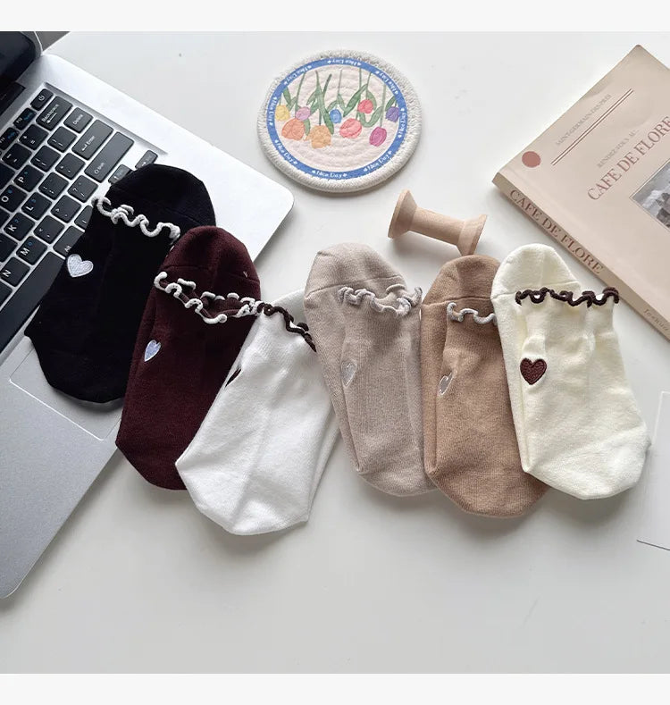 A collection of embroidered yoga socks in various neutral tones, including black, brown, cream, and beige.