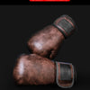 A pair of brown leather boxing gloves shown against a dark background.