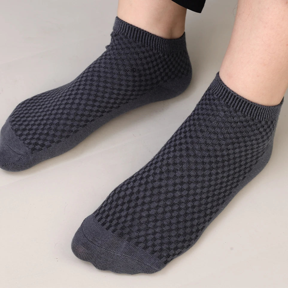 A pair of dark gray knitted bamboo fibre anti-odor socks shown on a person's foot.