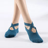 A model's feet are shown wearing teal silicone yoga and pilates socks.