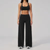 A woman wearing a black two-piece yoga and sports tracksuit set consisting of a cropped top and loose pants.