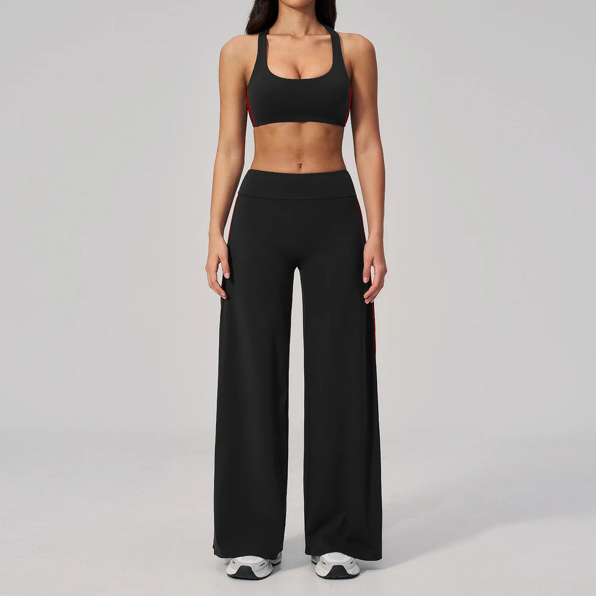A woman wearing a black two-piece yoga and sports tracksuit set consisting of a cropped top and loose pants.