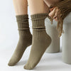 A pair of olive green thick cotton tube socks being pulled onto a person's foot.
