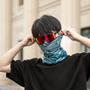 Eine Person mit orange getöntem Fahrradhelm und blau gemustertem Gesichtsmaske wird im Freien gezeigt.
