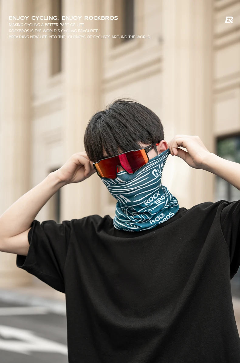 Eine Person mit orange getöntem Fahrradhelm und blau gemustertem Gesichtsmaske wird im Freien gezeigt.