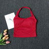A red seamless yoga and pilates sports bra laid on a dark gray fabric with some dried flowers nearby.