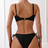 Eine Frau von hinten, die ein schwarzes String-Bikini-Set mit hoher Taille trägt.