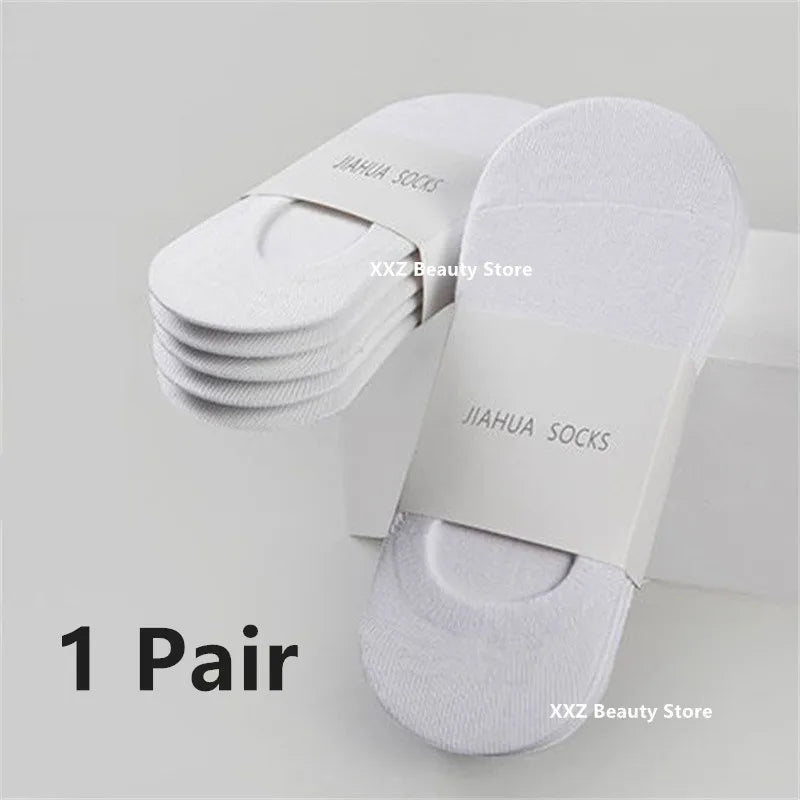 A pair of white invisible silicone no-show boat socks stacked on a white box.