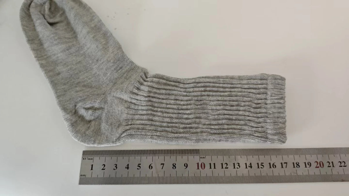 Calcetines de punto grises dispuestos junto a una regla que muestra su longitud.