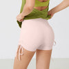 A person wearing light pink performance yoga shorts and a green top, showing the fit and fabric.