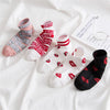 A pair of funny lettered striped socks in pink and white are displayed on a white fabric with a note.