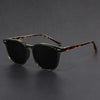 A pair of tortoiseshell-framed, dark sunglasses resting on a dark surface.