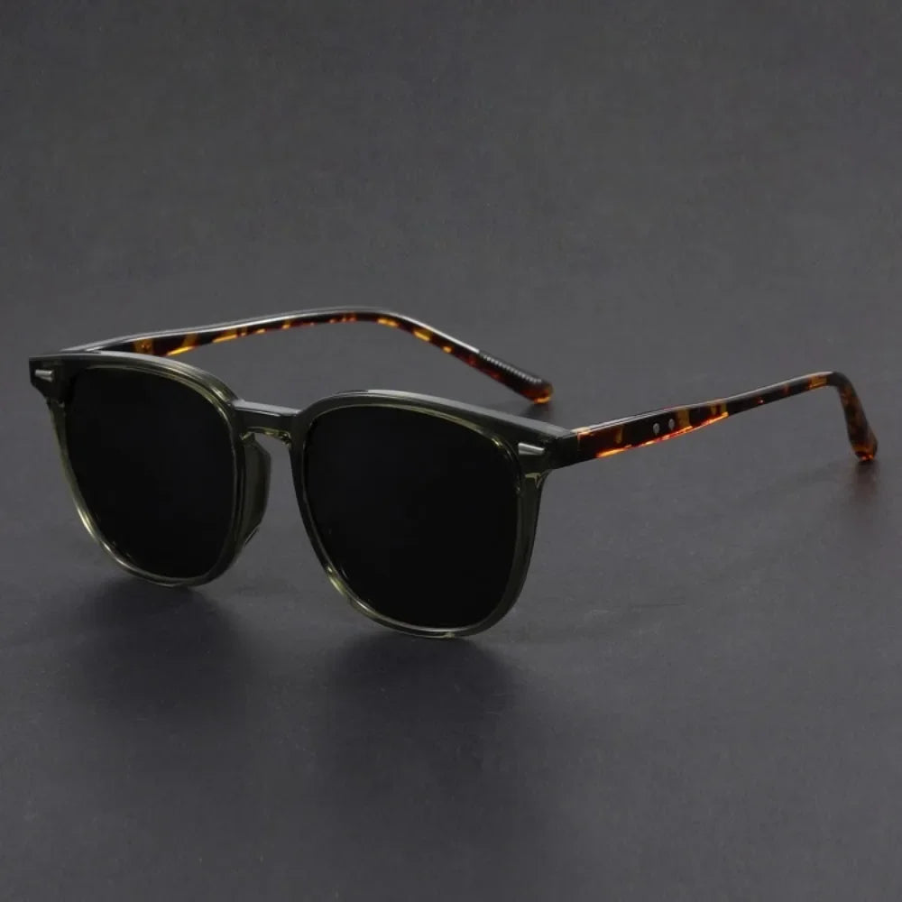 A pair of tortoiseshell-framed, dark sunglasses resting on a dark surface.