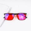 A pair of red tinted blue light blocking glasses resting on a white spiral notebook.