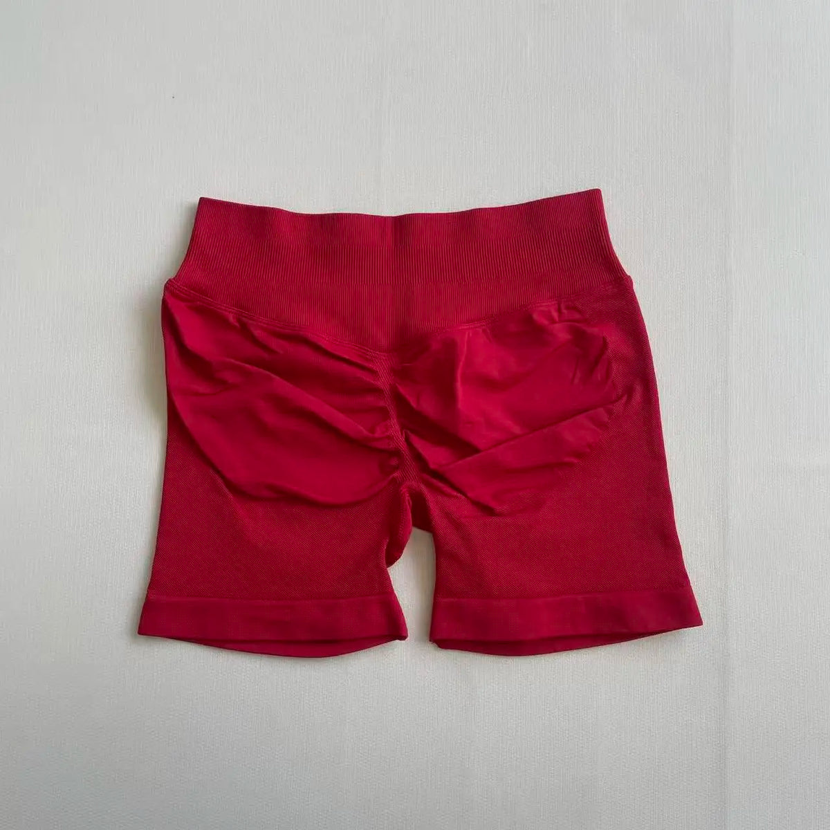 A pair of red seamless high-waisted yoga shorts laid flat on a white surface.