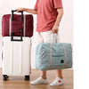 A person is holding a white rolling suitcase and a light blue duffel bag.