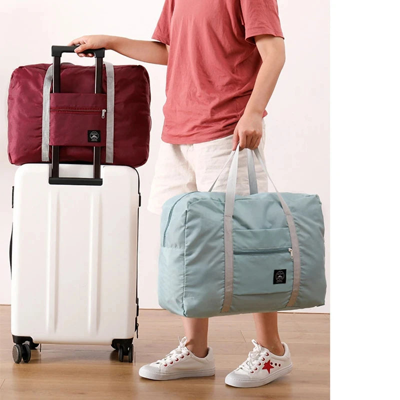 A person is holding a white rolling suitcase and a light blue duffel bag.