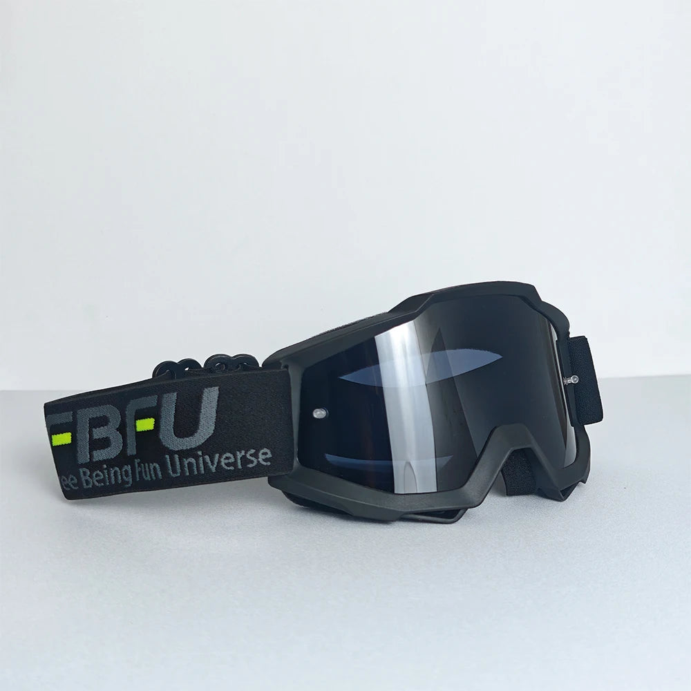 Black sport-grade skiing goggles with a clear lens and black strap resting on a white surface.