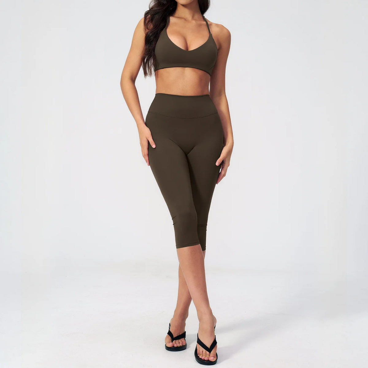 A woman wearing a dark olive green women's premium fitness tracksuit top and leggings.