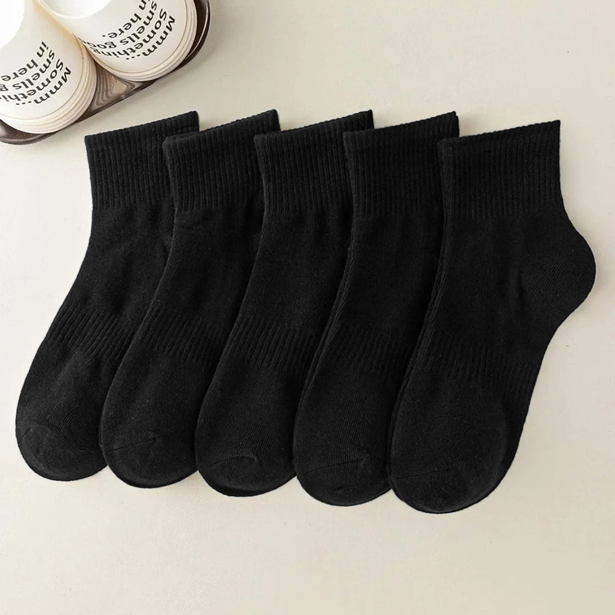 A row of black athletic crew socks laid flat on a light surface.