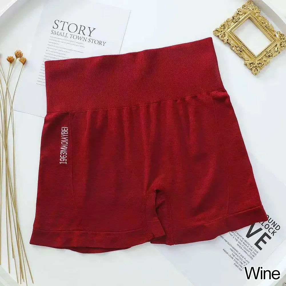 Un par de shorts deportivos sin costuras de fitness de color granate para mujer, colocados planos sobre una superficie blanca