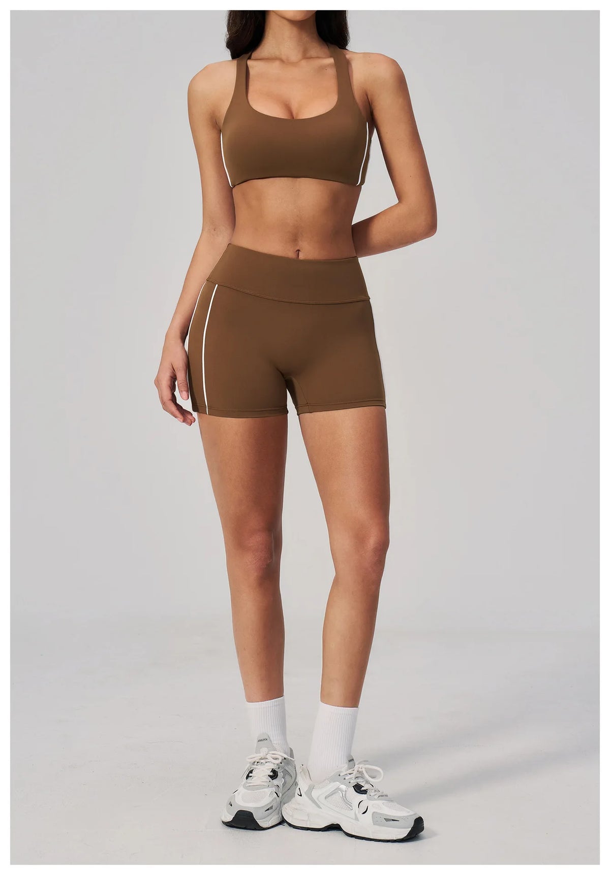 A woman models a brown two-piece yoga and sports tracksuit set featuring a cropped top and shorts.