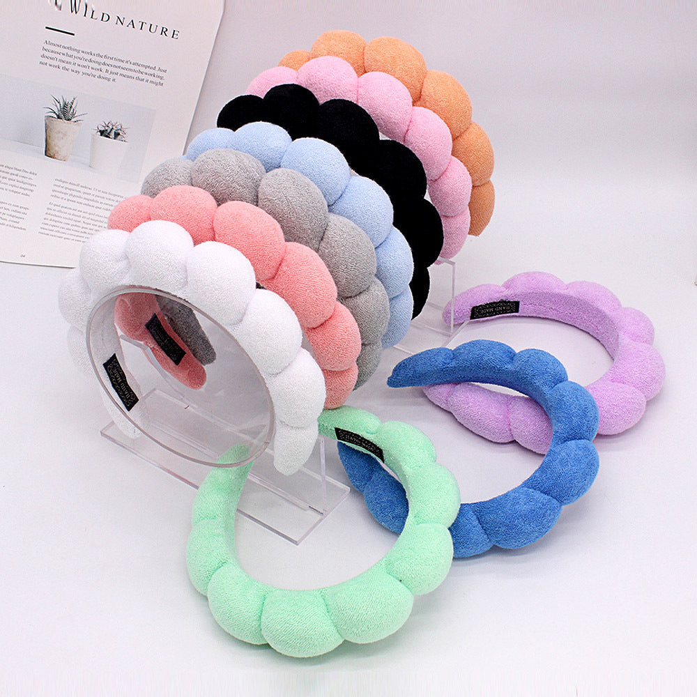 A display of colorful sponge terry cloth headbands for hair styling in various shades of pink, purple, blue, and black.