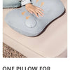 A gray inflatable pillow is shown being used for neck and lumbar support on a person's hand.