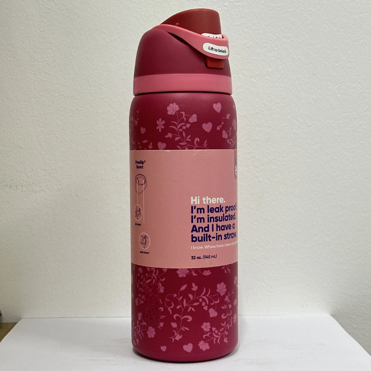 A pink vacuum insulated water bottle with a straw and a lid is shown standing upright against a white background.